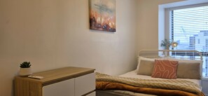 Un dormitorio con cama, mesita de noche y ventana con persianas.