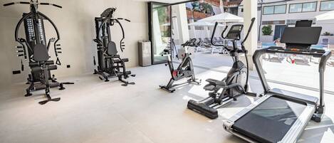 A gym with various exercise equipment, including a treadmill, stationary bikes, and weight machines.