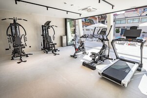 Un gimnasio con equipos de ejercicio variados, incluyendo cintas de correr, bicicletas estáticas y máquinas de pesas.