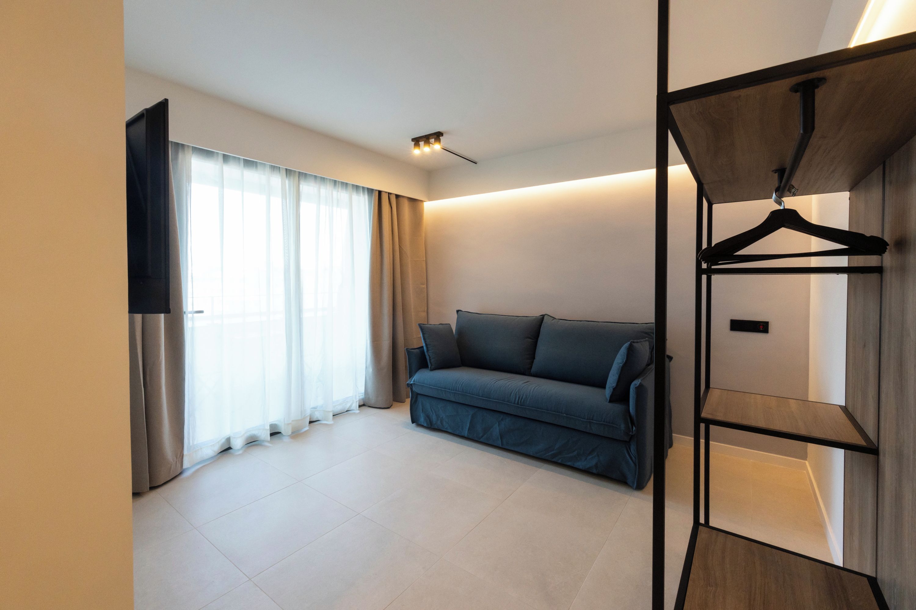 Una habitación moderna con un sofá, un televisor y un perchero de madera.