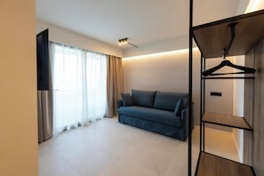 A modern room with a sofa, a TV, and a wooden hanger rack.