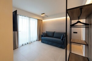 Una habitación moderna con un sofá, un televisor y un perchero de madera.