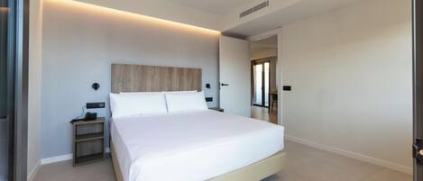 Une chambre à coucher moderne avec un grand lit, des tables de chevet et une tête de lit en bois.