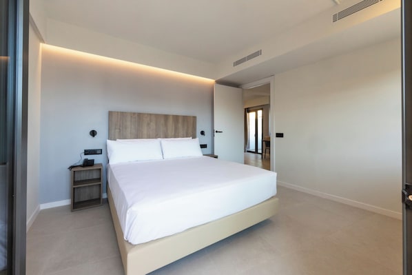 A modern bedroom with a large bed, bedside tables, and a wooden headboard.