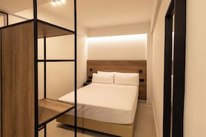 Una habitación de hotel moderna con una cama, una mesita de noche y un panel de madera.