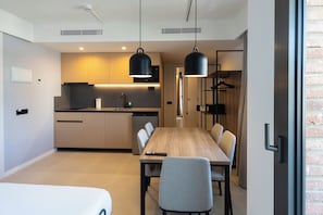 Et moderne køkken med træskabe, en indbygget ovn og en sort hængende lampe.