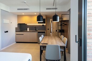 Una cocina moderna con armarios de madera, horno empotrado y una lámpara colgante negra.