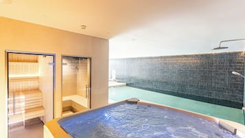 Un área de spa con una bañera de hidromasaje, una sauna y una zona de ducha con pared de vidrio.