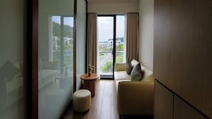 Une chambre d’hôtel moderne équipée d’un canapé, d’un pouf et d’un ventilateur de plafond.