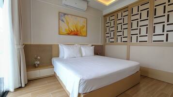 Une chambre d’hôtel comprenant un lit, un climatiseur fixé au mur, un panneau décoratif mural et une fenêtre avec des rideaux.