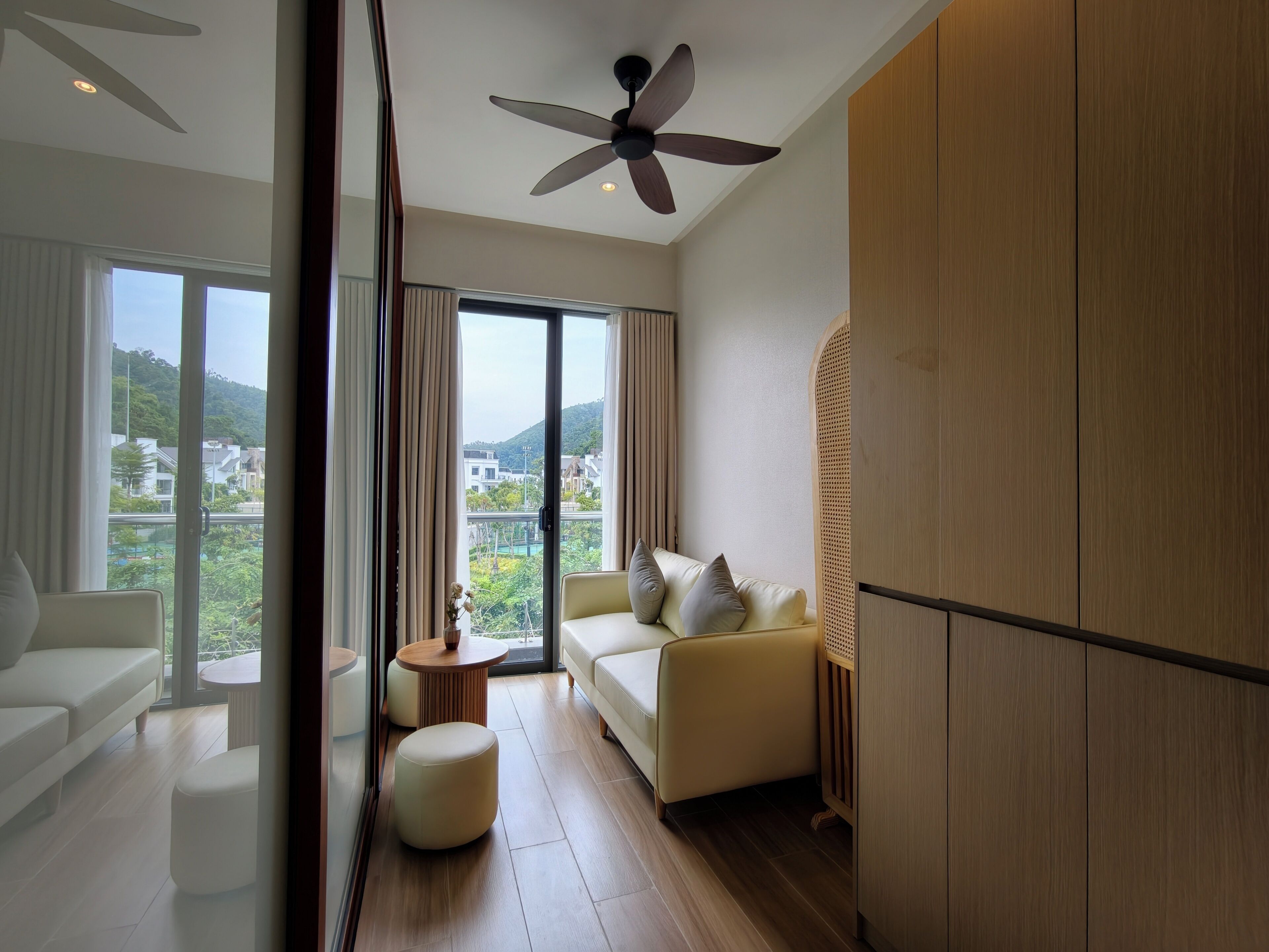 Un soggiorno moderno con divano, poggiapiedi e ventilatore a soffitto.