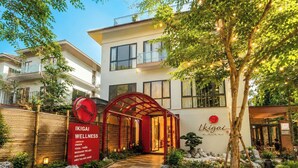 Un centre de bien-être avec une entrée rouge, un chemin de pierre et de la verdure.
