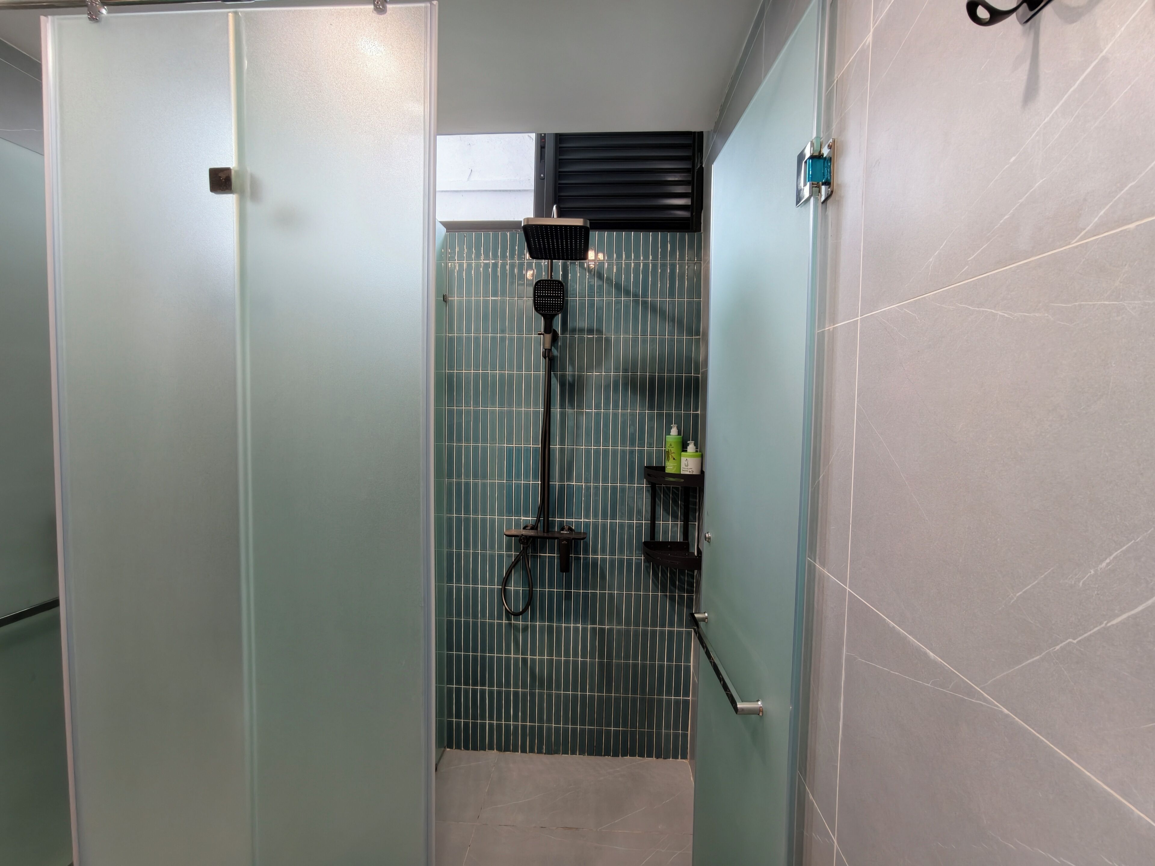 A bathroom with a shower area, a towel rack, and a shelf with toiletries.