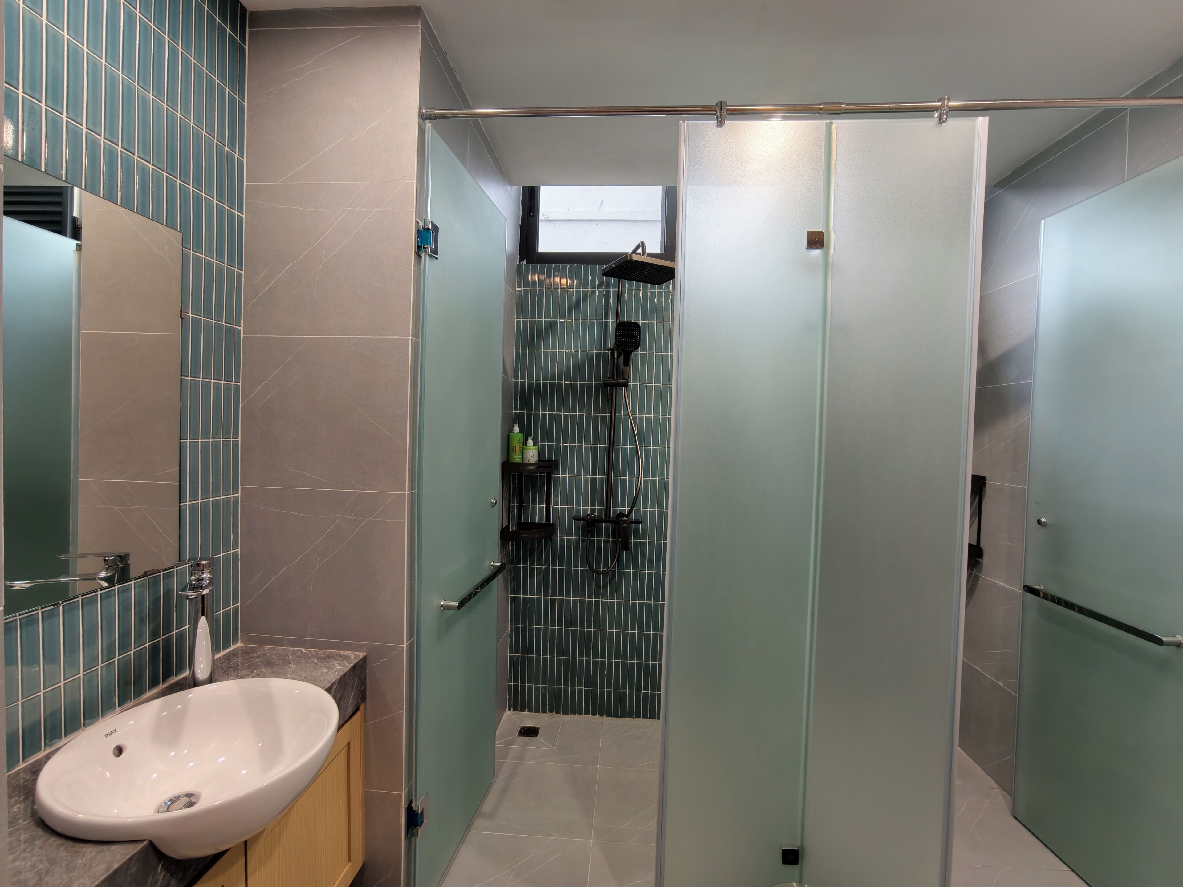 A modern bathroom with a sink, mirror, and shower area.
