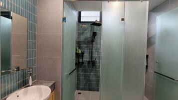 A modern bathroom with a sink, mirror, and shower area.