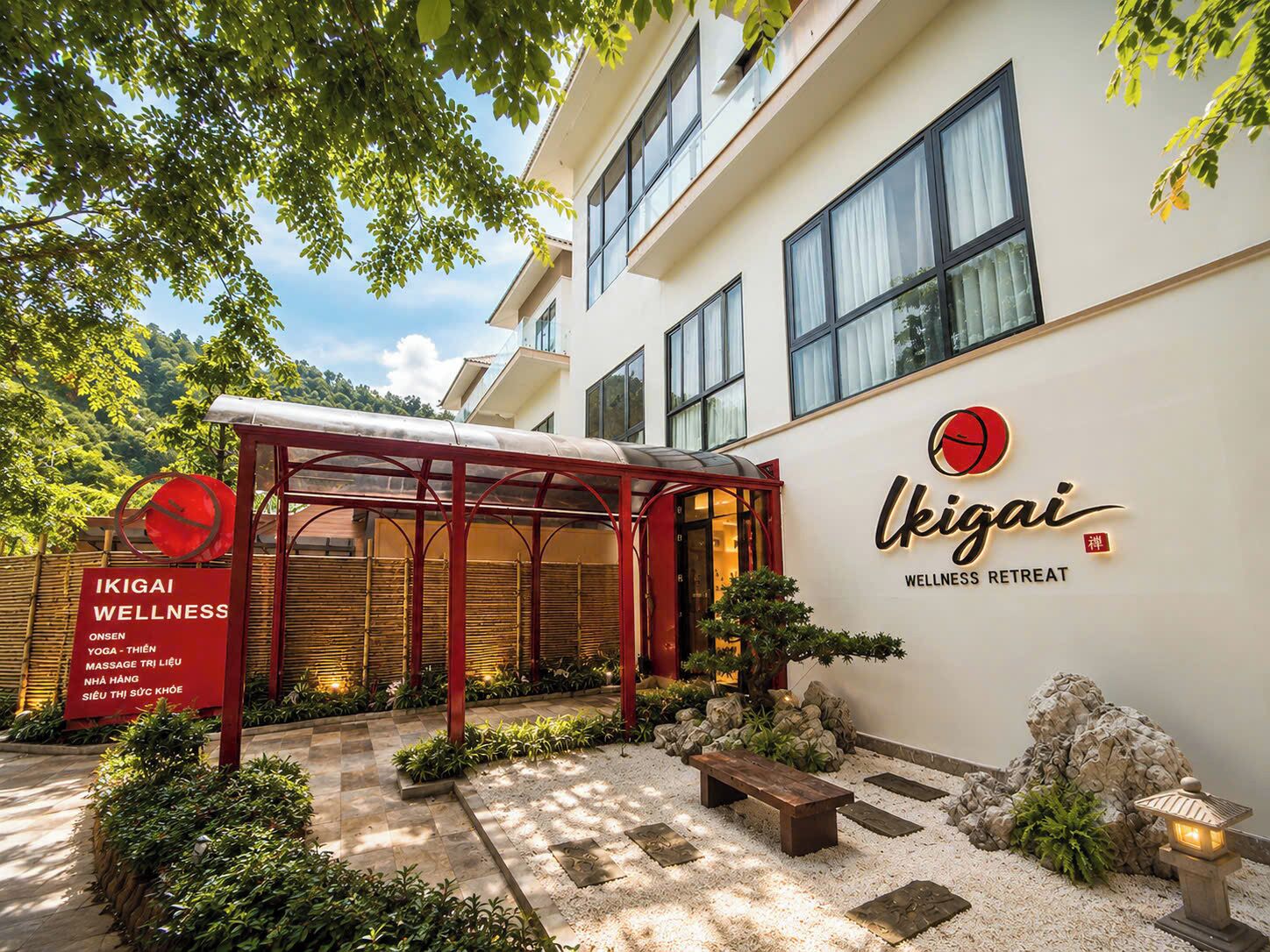 A wellness retreat with a covered outdoor area, a signboard listing services like yoga and massage, and a building with a wellness retreat sign.