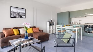 Een moderne woonkamer met een bank, salontafel en een eetgedeelte met stoelen en een tafel.