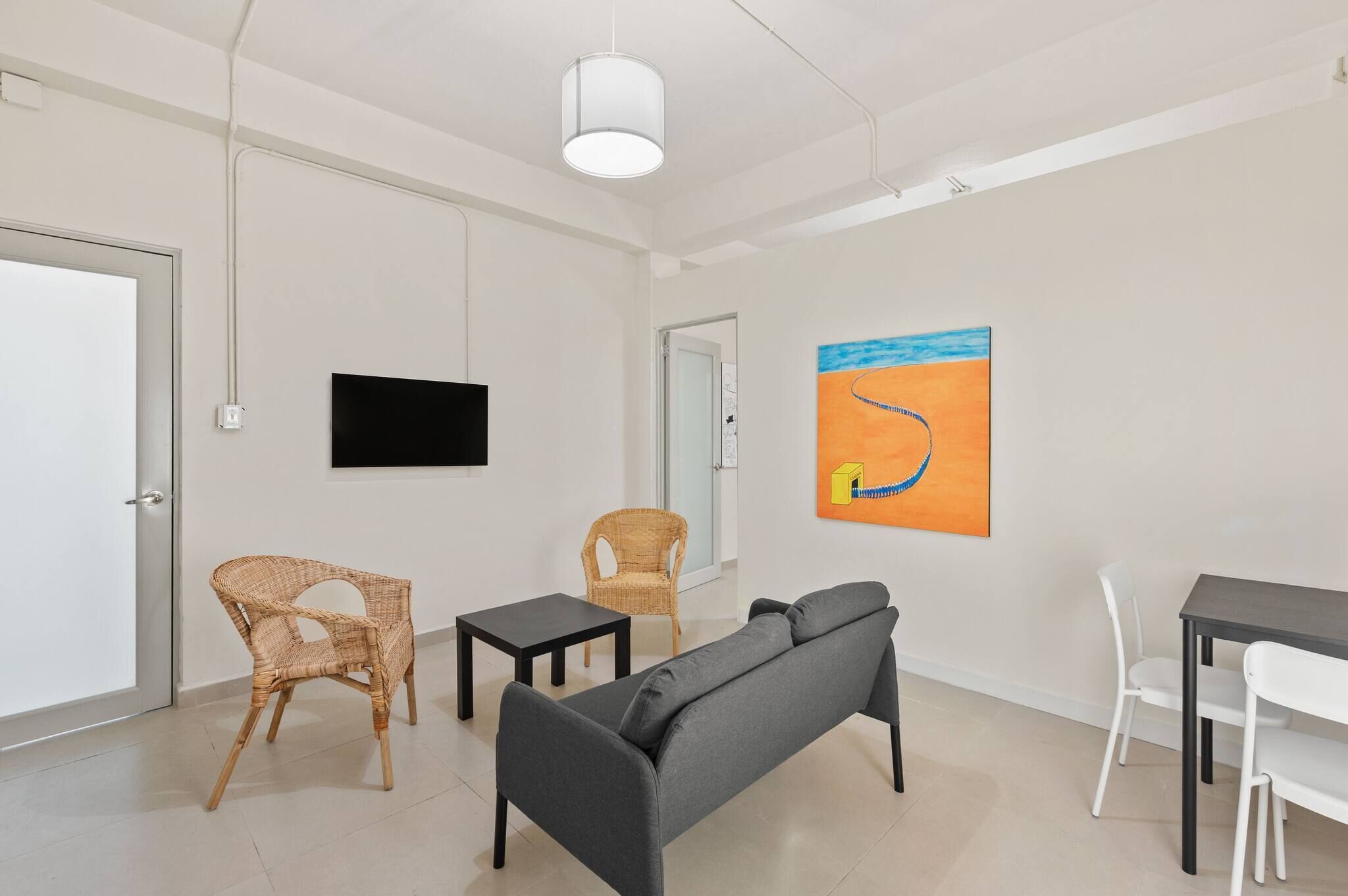 Une pièce moderne comprenant un canapé, deux fauteuils, une petite table, un téléviseur et un tableau accroché au mur.