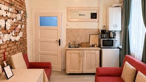 Ett kompakt bostadsutrymme med ett litet kök, en matplats och en sittgrupp.