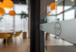 Schild eines Bed & Breakfast Hotels mit modernem Ambiente, darunter runde Tische und orangefarbene Pendelleuchten.