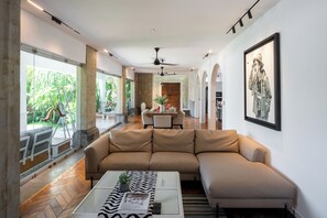 Un salon moderne avec un canapé d’angle beige, une table basse et un coin repas à l’arrière-plan.