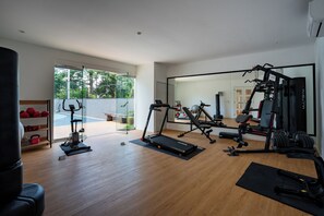 Une salle de sport moderne, équipée de matériel d’exercice, d’un tapis de course et d’un banc de musculation.