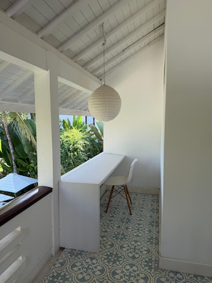 Una habitación con un escritorio blanco, una silla blanca, una lámpara colgante y baldosas de suelo estampadas.