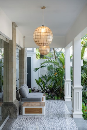 A modern interior with a sofa, a wooden coffee table, patterned floor tiles, and a hanging spherical light fixture. - Boutique Hotel Villa Kaui collections (Ubud)