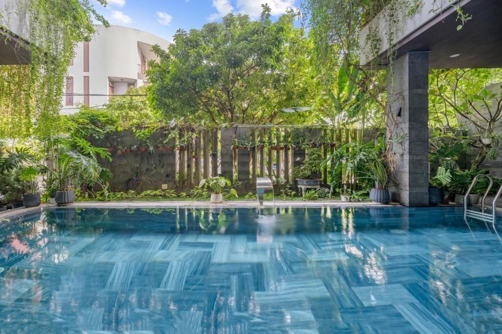 Ein Swimmingpool, umgeben von üppiger Vegetation und einem modernen Gebäude im Hintergrund.