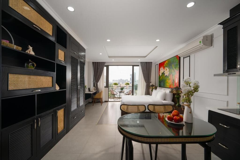 Une chambre d’hôtel moderne avec un balcon, un coin repas doté d’une table en verre et un grand tableau accroché au mur.