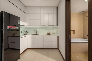 Una cucina compatta con mobili bianchi, forno integrato e pannello schienale in vetro.