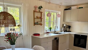 Et moderne køkken med hvide skabe, et spisebord med stole og en hængende lampe.