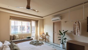 Una camera d'albergo con un letto, una scrivania, una sedia, una pianta in vaso e un armadio.