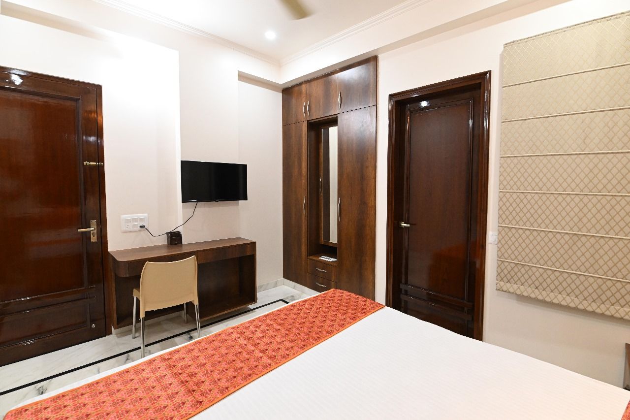 Een hotelkamer met een bed, een bureau, een stoel, een televisie en een kledingkast.