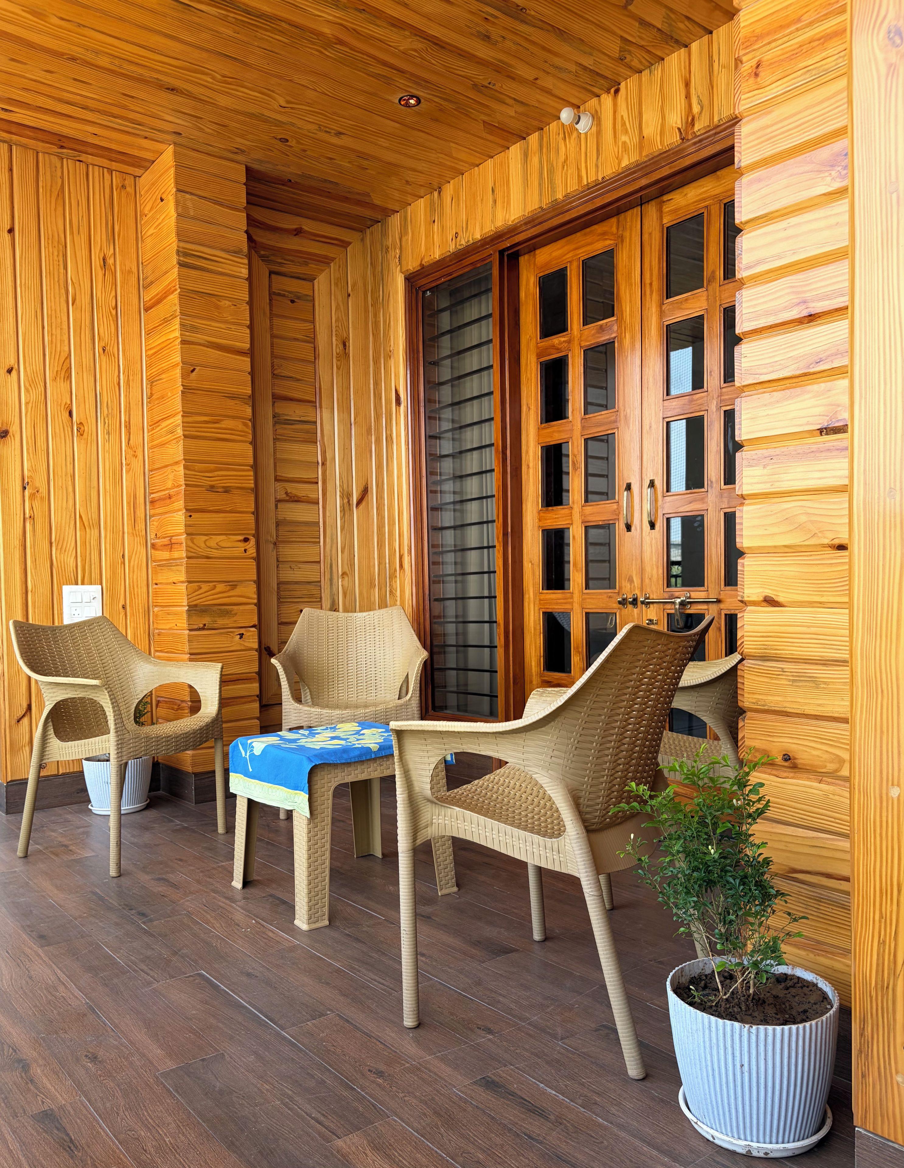 A wooden interior with wicker furniture, a table with a blue tablecloth, and a potted plant.