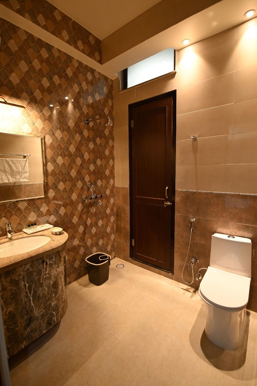 A bathroom with a marble sink, a dark wooden door, and a white toilet.