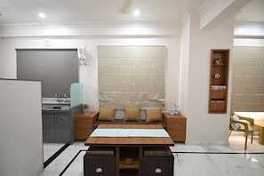 A modern kitchen with a built-in oven, a dining area with a table and chairs, and a large window with a patterned curtain. - Hadendra Residences - A Boutique Homestay in Jaipur (Jaipur)