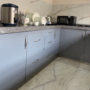A kitchen with grey cabinets, a granite countertop, and a microwave. - Hadendra Residences - A Boutique Homestay in Jaipur (Jaipur)