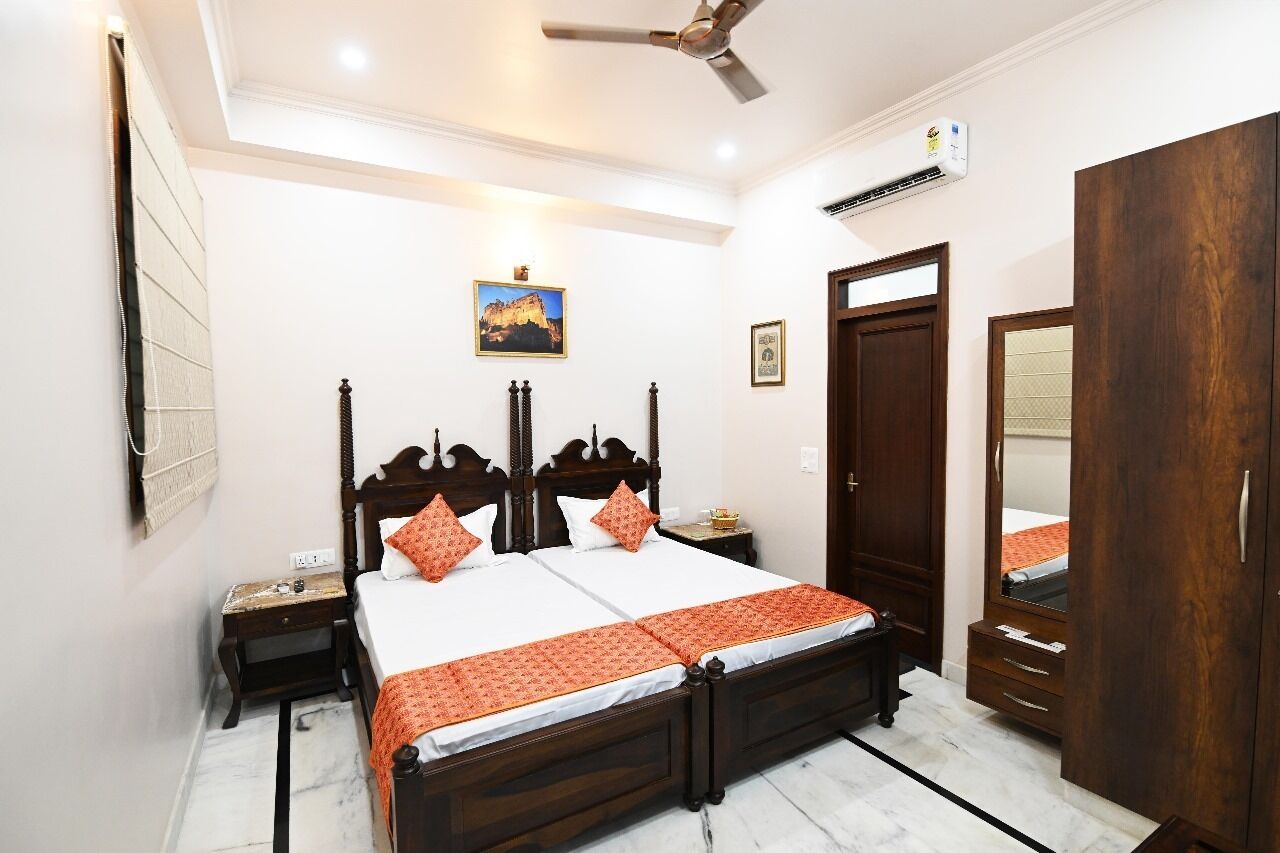 A bedroom with a bed, bedside tables, a wardrobe, a ceiling fan, and an air conditioning unit.