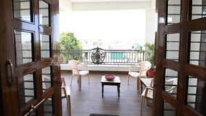 Un balcón con vistas a edificios, barandilla y una mesa con sillas.