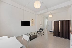 A modern interior with a glass table, white chairs, artwork on the walls, and a TV. - Barrio Sanctuary - Villa Serena (San Juan)
