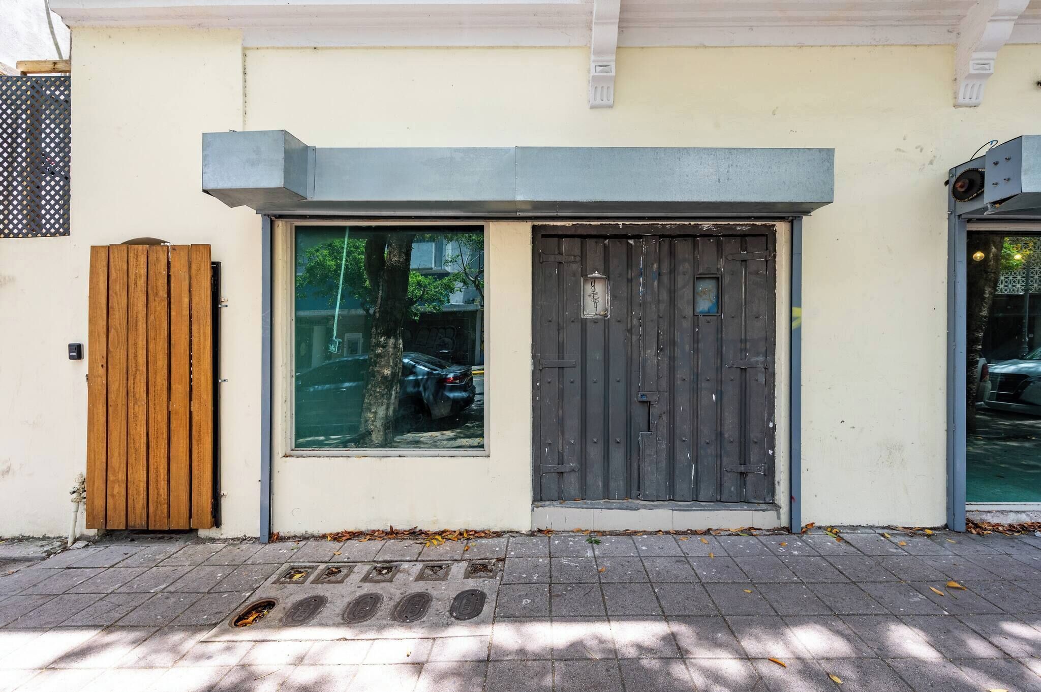 Une façade d’immeuble avec une porte en bois, une fenêtre et un portail en métal.
