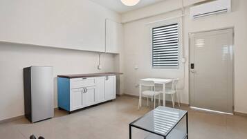 A modern kitchen with a refrigerator, a blue cabinet, a white table, and a glass partition.