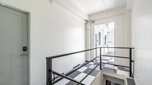 Eine Treppe mit schwarz-weiß kariertem Boden, einem Metallgeländer und einer Tür mit einem Zahlenschloss.