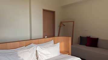 A hotel room with a bed, a wooden headboard, a sofa, and a door.