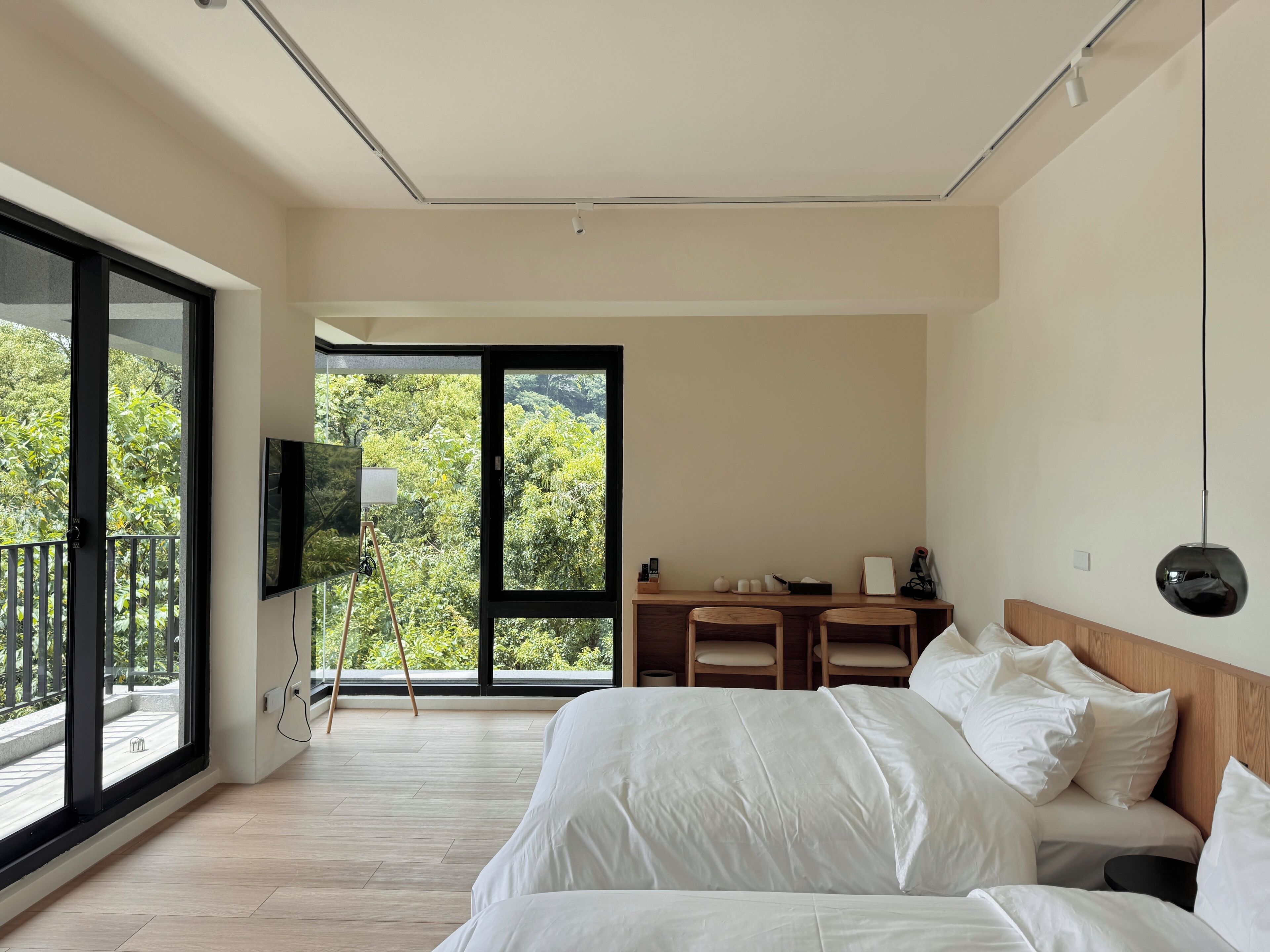 A modern bedroom with a large bed, a desk, and a TV.