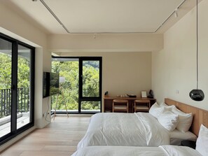Un dormitorio moderno con una cama grande, un escritorio y un televisor.