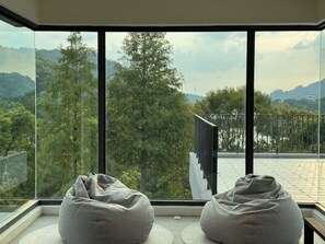 A room with a large window overlooking a mountainous landscape. There are two bean bags on the floor.