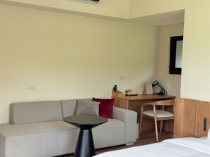 Habitación de hotel con sofá, una mesita, escritorio con silla y cama.