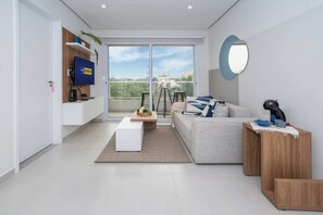 Una sala moderna con un sofá, una mesa de centro y un televisor montado en la pared.